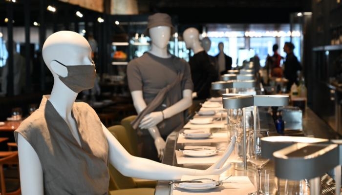 مطعم يعرض الملابس على تماثيل بين الطاولات بهدف البيع والحفاظ على التباعد